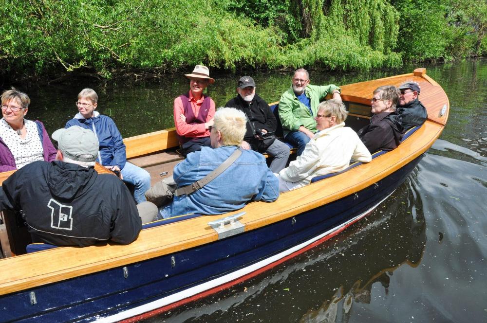 Eine Gruppe in einem Holzboot auf dem Fluss — Erzählfahrt auf dem Wasser